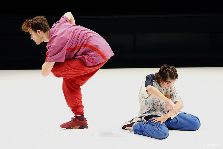 Tänzer:innen Sofiia Stasiv (kniend auf dem Boden) und Denis Cvetković (in einer stehenden, leicht gebeugten Position).